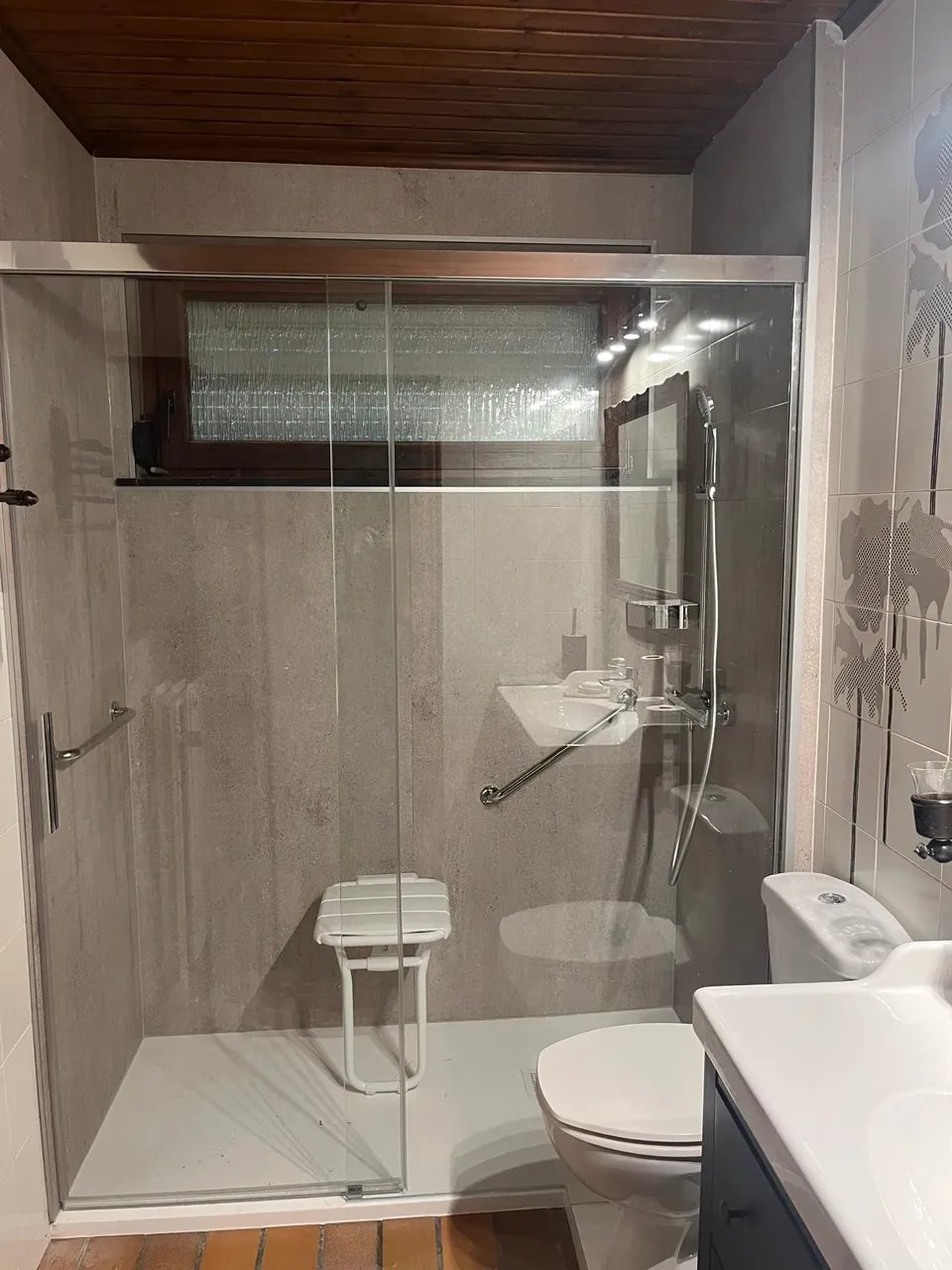 Douche senior de plain-pied avec siège rabattable et barre d'appui, réalisée par AV.Renove à Seraing